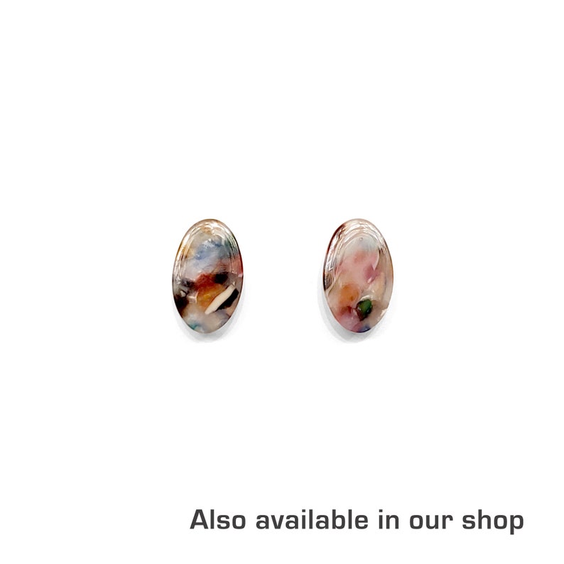 May include: A pair of oval-shaped earrings with a colourful, marbled pattern. The earrings are made of resin and have a white background with brown, pink, and blue swirls.