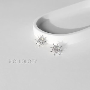 Pair of silver sunburst stud earrings in front of a white tray