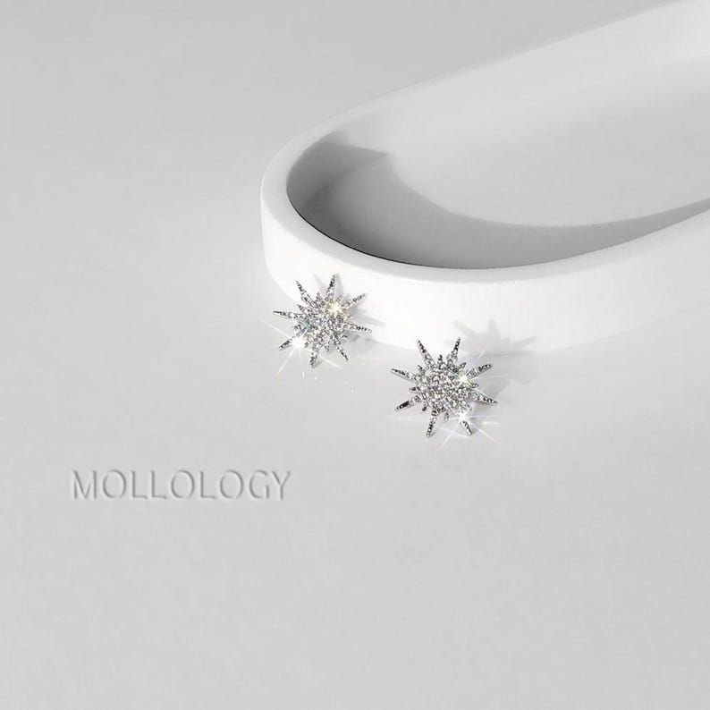 Pair of silver sunburst stud earrings in front of a white tray