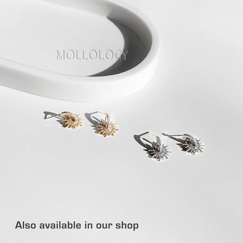 May include: Two pairs of earrings with a sunburst design. One pair is gold with clear crystals, the other is silver with clear crystals.
