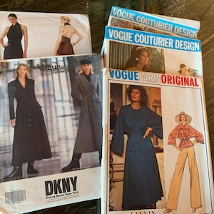 May include: A collection of vintage Vogue sewing patterns featuring fashion designs. The patterns showcase various styles, including dresses and coats. The DKNY pattern is visible, along with the text "VOGUE COUTURIER DESIGN" and "VOGUE PARIS ORIGINAL".