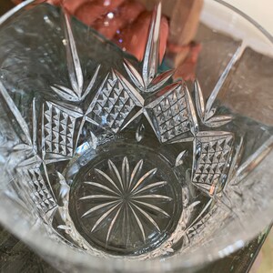 K&ouml;nnte beinhalten: Ein klares Glas mit geschnittenem Kristallmuster. Der Boden des Glases hat ein Sternmuster.