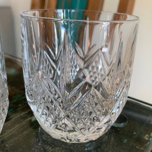 K&ouml;nnte beinhalten: Zwei klare Glasbecher mit geschliffenem Kristallmuster. Die Gl&auml;ser sind leer und stehen auf einer Holzoberfl&auml;che.