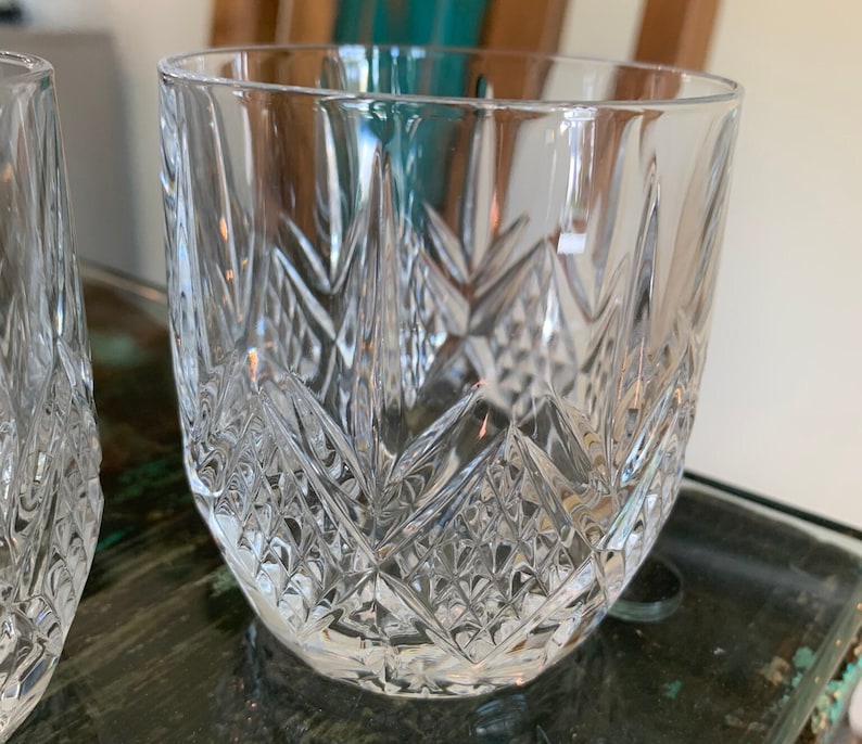 K&ouml;nnte beinhalten: Zwei klare Glasbecher mit geschliffenem Kristallmuster. Die Gl&auml;ser sind leer und stehen auf einer Holzoberfl&auml;che.