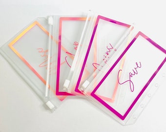Könnte beinhalten: Vier transparente Plastik-Reißverschlusstaschen mit rosa und orangenen Rändern. Die Taschen haben handschriftliche Texte: "Dream", "Imagine", "Trust" und "Save".