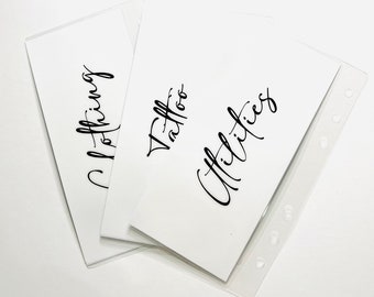May include: Three white cards with black handwritten text. The cards are labeled "Clothing", "Tattoo", and "Utilities".