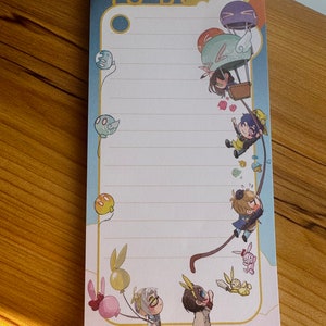Puede incluir: Un bloc de notas blanco con un borde de arcoíris y la palabra "TO DO" en letras doradas. El bloc de notas presenta ilustraciones de personajes de dibujos animados con globos y un globo aerostático.
