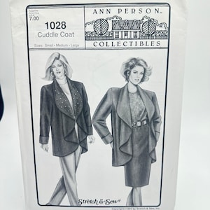 Könnte beinhalten: Ein weißer Schnittmusterumschlag für den Ann Person Collectibles Cuddle Coat, Modell 1028. Die Vorderseite zeigt schwarz-weiße Illustrationen von zwei Mänteln mit drapierten Revers, einer davon mit Nieten, und enthält die Größen Small, Medium und Large.