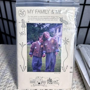 May include: A package for a children's jacket sewing pattern. The package features a photo of two children wearing the jacket. The jacket is brown with decorative elements. The text on the package reads "MY FAMILY & ME".