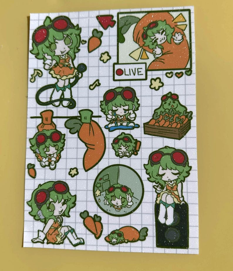 May include: A sticker sheet featuring a grid background with multiple illustrations of a green-haired character wearing red goggles and an orange outfit. The sheet includes various poses, carrots, a crate of carrots, and a box labelled OLIVE.