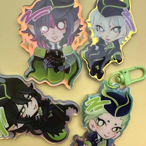 Puede incluir: Cuatro llaveros de personajes de estilo anime con bordes iridiscentes y cierres verdes. Los personajes tienen cabello oscuro, detalles en verde y morado y visten uniformes oscuros. Los llaveros est&aacute;n sobre un fondo amarillo.