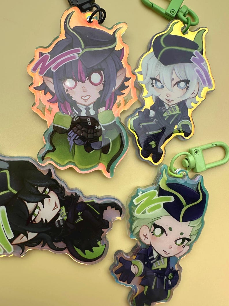 Puede incluir: Cuatro llaveros de personajes de estilo anime con bordes iridiscentes y cierres verdes. Los personajes tienen cabello oscuro, detalles en verde y morado y visten uniformes oscuros. Los llaveros est&aacute;n sobre un fondo amarillo.