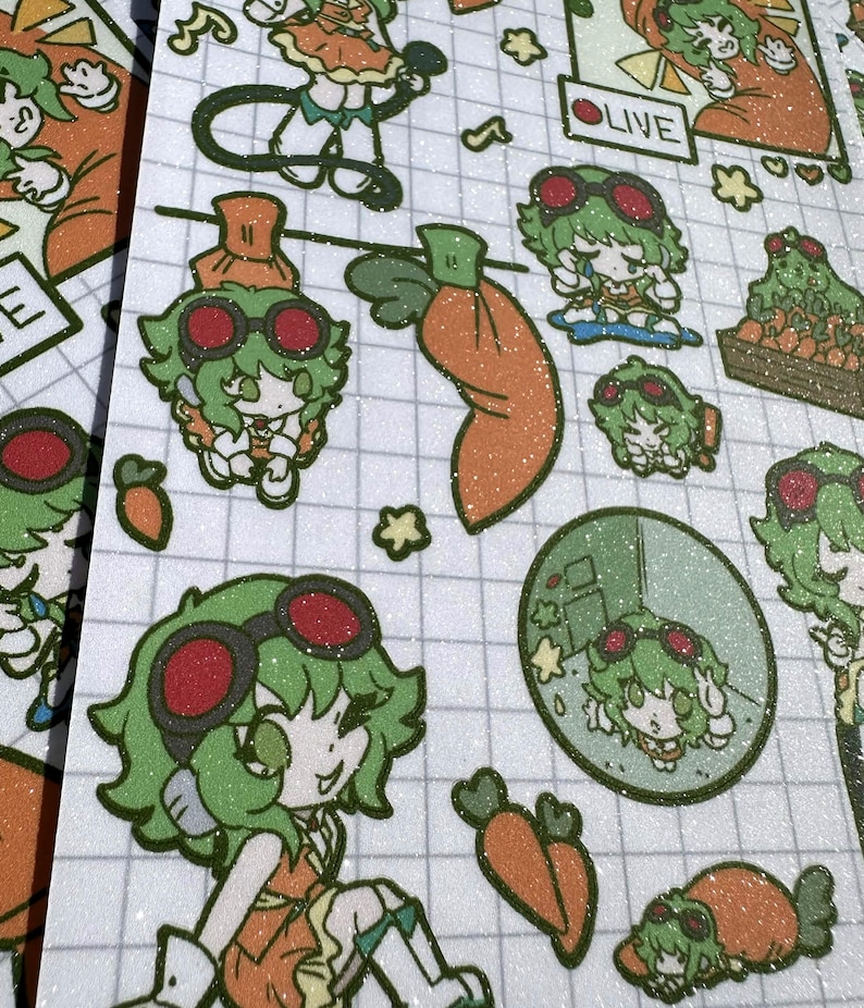 May include: A glittery sticker sheet featuring multiple cartoon illustrations of a green-haired character wearing red goggles and an orange outfit. The designs include the character with carrots, a live stream frame, and various poses on a grid background.