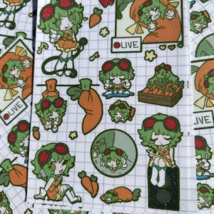 May include: A sticker sheet featuring a grid pattern background with multiple illustrations of a green-haired character wearing red goggles and an orange outfit, alongside various carrot icons and a box of carrots with the text LIVE in a box.