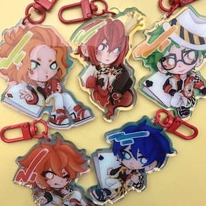 Puede incluir: Llaveros acr&iacute;licos con personajes de estilo anime con cierres rojos de pinza de langosta. Los llaveros muestran personajes con varios colores de cabello, atuendos y motivos de naipes. Cada personaje est&aacute; representado en un estilo chibi, con colores vibrantes y dise&ntilde;os detallados.