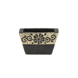 May include: A black and gold rectangular planter with a floral design. The planter has a textured surface and a wide, rectangular opening.