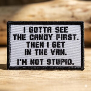 May include: A rectangular patch with black embroidered text on a light gray background. The text reads: "I GOTTA SEE THE CANDY FIRST. THEN I GET IN THE VAN. I'M NOT STUPID." The patch has a black border.