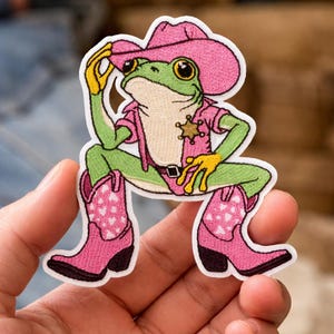 May include: A white ceramic mug with a black handle and the text "But First, Coffee" in a black, handwritten-style font. The mug is on a white surface.