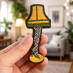 May include: A set of three ceramic mugs with a speckled, cream-colored glaze. Each mug features a different hand-painted design: a blue and green leaf, a yellow flower, and a red berry. The mugs have a simple, rounded shape.