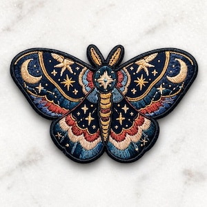 May include: Embroidered moth patch with a celestial design. The patch features a navy blue background with gold stars, crescent moons, and a central starburst. The moth's wings have red, blue, and gold accents, creating a detailed and colorful design.