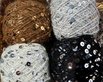 May include: Four balls of yarn with sequins, in brown, gray, white, and black.