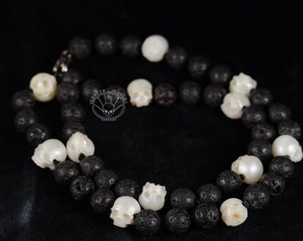 Puede incluir: Un collar de cuentas de lava negra y calavera blanca. El collar está hecho de cuentas de lava negra y calavera blanca alternas.