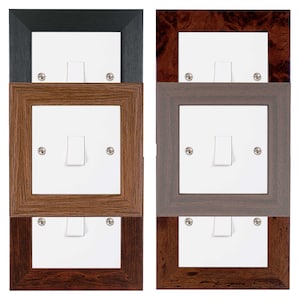 May include: Three white light switch plates in different coloured frames. The top frame is black, the middle frame is brown wood, and the bottom frame is dark brown wood.
