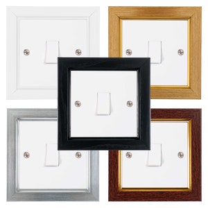 May include: Four light switch plates in different frames. The frames are white, gold, black, and mahogany.