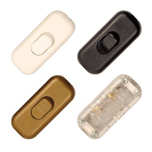 May include: Four inline light switch toggles in different colours: white, black, gold, and clear. The switches are rectangular and have a single toggle button.