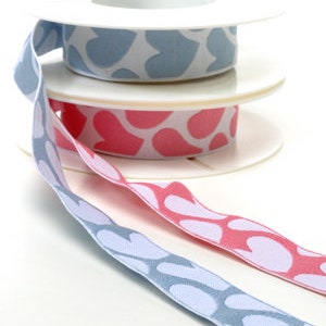 Può includere: Due bobine di nastro con cuori bianchi su sfondo blu e rosa. Il nastro è su bobine bianche.