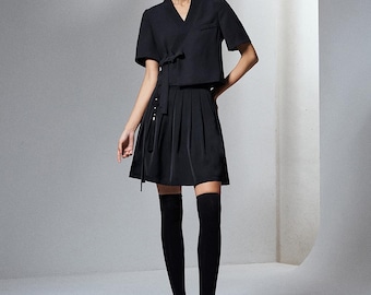 May include: A black short-sleeved wrap top with a side tie closure paired with a black pleated mini skirt. The outfit includes black over-the-knee socks and black pointed-toe high-heeled shoes, creating a monochromatic ensemble.