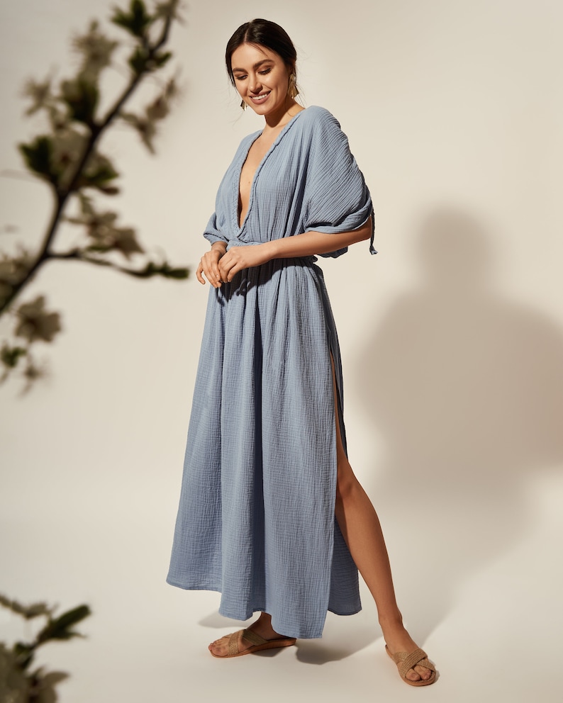K&ouml;nnte beinhalten: Ein hellblaues Maxikleid mit tiefem V-Ausschnitt und einem Schlitz an der Seite. Das Kleid hat eine lockere Passform und ist aus einem weichen, leichten Stoff gefertigt.