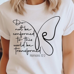 以下が含まれることがあります： 黒い蝶のグラフィックと「この世に同化しないで、変えられてください」というテキストと「ローマ人への手紙 12:2」が書かれた白いTシャツ。