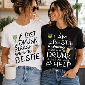 Könnte beinhalten: Ein weißes T-Shirt mit schwarzem Text IF LOST OR DRUNK PLEASE RETURN TO BESTIE und ein schwarzes T-Shirt mit weißem Text I AM THE BESTIE warning BESTIE MAY BE DRUNK & LOST AS WELL just send HELP, beide mit aufgedruckten Cocktail-Grafiken.