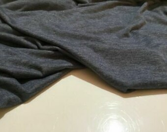 Puede incluir: Un primer plano de una tela suave y azul con una superficie ligeramente texturizada. La tela está doblada y drapeada, mostrando su caída y textura.