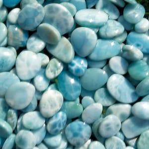 Peut inclure: Gros plan sur une collection de cabochons de pierres précieuses lisses, bleu clair et blanc. Les pierres ont une apparence marbrée et irisée.