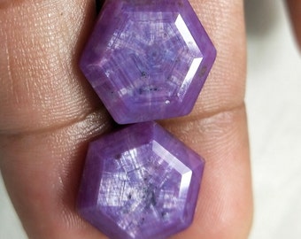 May include: Two purple hexagonal faceted gemstones with a star-like pattern.