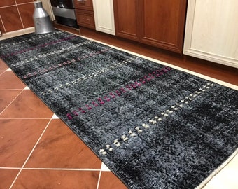 Puede incluir: Una alfombra de pasillo negra y blanca con detalles en rosa. La alfombra tiene un patrón geométrico y está hecha de un material suave y texturizado.