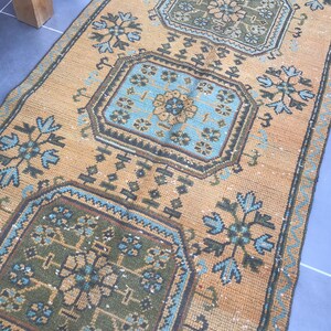 Puede incluir: Una alfombra de color marr&oacute;n claro y azul con un dise&ntilde;o geom&eacute;trico. La alfombra tiene un aspecto descolorido y est&aacute; hecha de un material tejido.