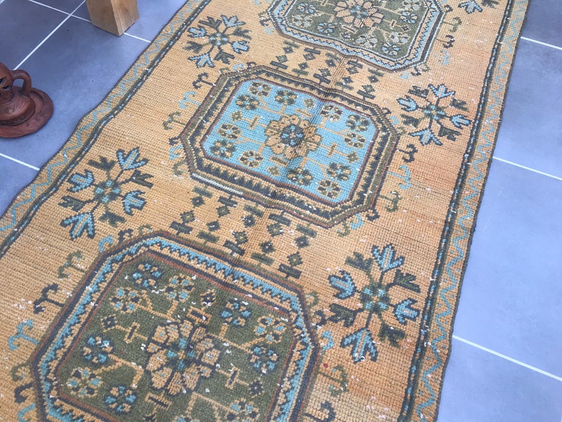 Puede incluir: Una alfombra de color marr&oacute;n claro y azul con un dise&ntilde;o geom&eacute;trico. La alfombra tiene un aspecto descolorido y est&aacute; hecha de un material tejido.