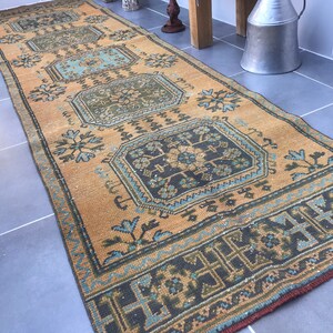 Puede incluir: Una alfombra de pasillo vintage con un fondo beige y patrones intrincados en tonos azules, verdes y negros. La alfombra tiene un aspecto desgastado y es perfecta para agregar un toque de estilo bohemio a cualquier habitaci&oacute;n.