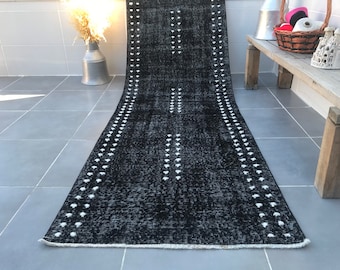 Puede incluir: Alfombra de pasillo negra y blanca con un patrón geométrico. La alfombra tiene un borde blanco con pequeños puntos blancos a lo largo de los bordes.
