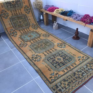 Puede incluir: Una alfombra larga y rectangular con un dise&ntilde;o persa tradicional. La alfombra es de color beige c&aacute;lido con intrincados patrones en tonos de azul, verde y negro. La alfombra es perfecta para agregar un toque de estilo tradicional a cualquier habitaci&oacute;n.