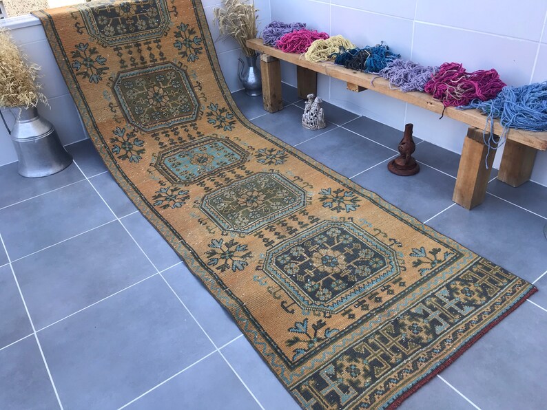 Puede incluir: Una alfombra larga y rectangular con un dise&ntilde;o persa tradicional. La alfombra es de color beige c&aacute;lido con intrincados patrones en tonos de azul, verde y negro. La alfombra es perfecta para agregar un toque de estilo tradicional a cualquier habitaci&oacute;n.