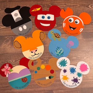 May include: Eight colorful Disney character-themed thank you tags. Each tag is shaped like Mickey Mouse's head and features a different character, including Mickey Mouse, Lightning McQueen, Dory, Simba, Ariel, and a paint palette. Each tag says "Thank You Housekeeping".