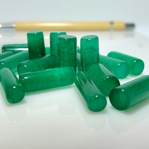 May include: A group of green jade stone beads, each shaped like a cylinder. The beads are smooth and polished, with a slight sheen.