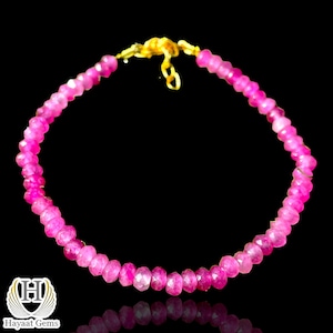 May include: A pink gemstone bracelet with a gold clasp. The bracelet is made of small, faceted beads.