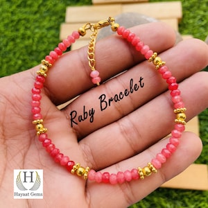 Op de afbeelding: Een roze en rode edelsteen armband met gouden accenten. De armband heeft een sluiting en is gelabeld "Ruby Bracelet".
