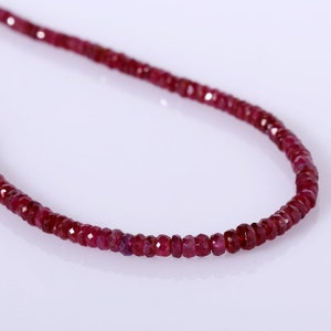 May include: A strand of ruby red gemstone beads strung on a thin cord. The beads are faceted and have a slightly irregular shape.