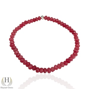 May include: A pink gemstone bracelet with a silver clasp. The bracelet is made of small, faceted beads.